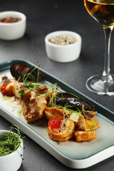 seafood plate with mussels and shrimp toped microgreen closeup with glass of white wine