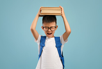 School Stress. Angry Asian Schoolboy Holding Books On Head And Shouting