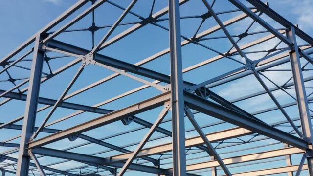 Metal construction - steel frame. Abstract structure (framework) consisting of iron girders and beams isolated against blue sky on a sunny day. Metalwork engineering - geometric grid structure.