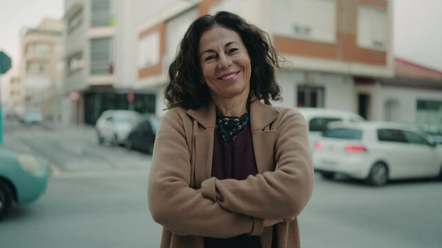 Middle age hispanic woman smiling confident standing with arms crossed gesture at street