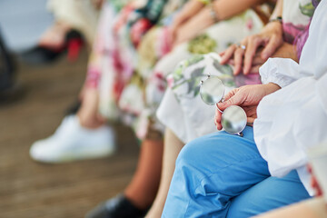 A woman holds round sunglasses in her hands. Hands close up.