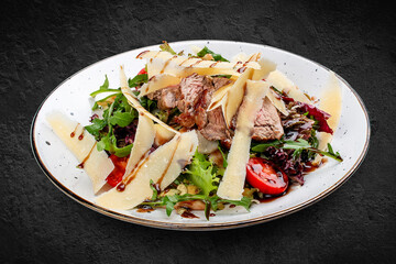 Veal and pear salad with olive-balsamic dressing. Isolated on a black background.