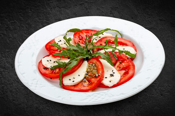 Caprese salad with mozzarella, tomatoes and pesto sauce. A traditional Italian dish. Isolated on a black background.