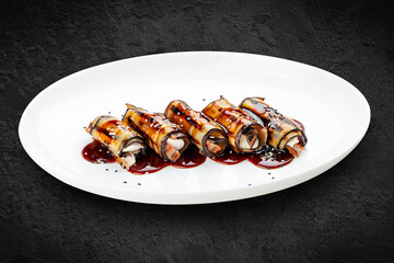 Eggplant rolls with eel. Isolated on a black background.