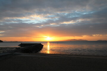 夜明けの海岸に一筋の光が照らし出す
