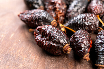 Dried wrinkled briar berries. Dry rose hips. Dog-rose fruits on a rustic wooden surface. Macro