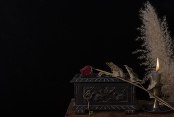 Dark still life with dried roses on wooden table.