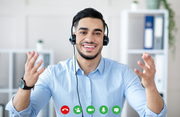 Head shot of Arab guy wearing headphones, using online communication service, having remote video...