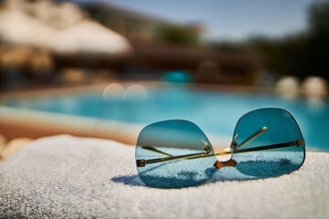 Beautiful sunglasses on the background of the pool. Relax by the pool. Sunglasses. 