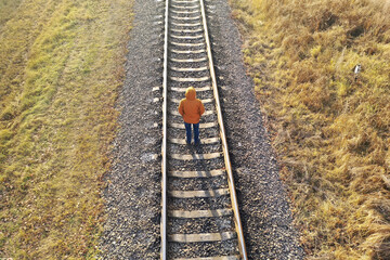 Loneliness concept. A man walks along the railway tracks, running away from himself. 