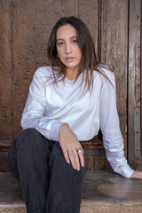 young woman sitting leaning against a wooden door