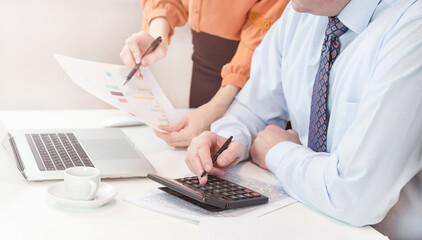 A man is sitting at a laptop. The manager explains the errors in the document to the employee.