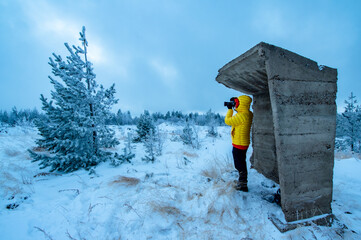 person in yellow jacket with camera on the hill in winter