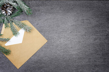 Christmas composition on a gray background with a fir branch, a cone and an envelope. Top view. Christmas. There is a place for the text.