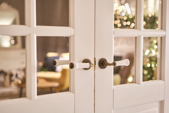 Beautiful Modern Door Knob. Christmas Lights On The Background. Open, Wooden Front Door From The Interior Of An Upscale Home With Windows.