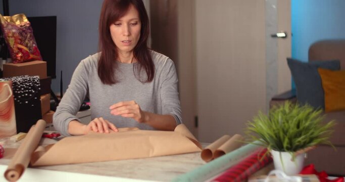 Woman packaging box with kraft wrapping paper. Happy holiday present and gifts. DIY art craft