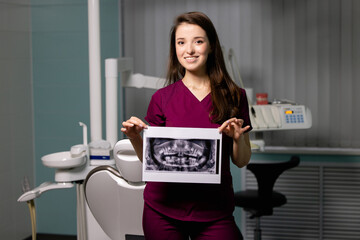 Beautiful woman doctor with dental scans in hands in a dental clinic