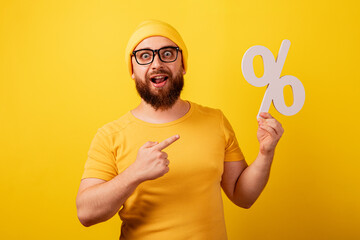 handsome man pointing at percent symbol over yellow background, concept of interest-free loan