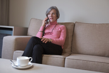 Older woman and cell phone, Senior female talking phone while sitting in home living room, retired people on call with happiness, communication technology lifestyle