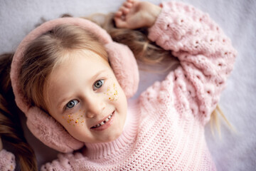 A little joyful girl in pink with sequins isolated on a white background. Children's holiday, christmas and birthday in winter. Children's cosmetics, dentistry, diastema. Selective focus