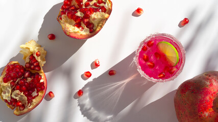 Summer cocktail with pomegranate and ice. Flat lay White table with sunlight. Summer, tropical and juicy concept