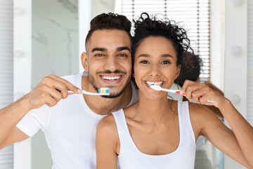 Cheerful Young Middle Eastern Couple Brushing Teeth Together And Smiling At Camera