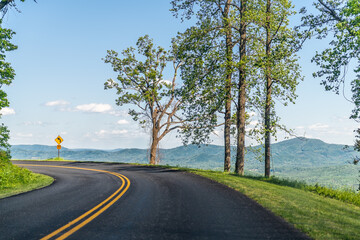 Fototapeta na wymiar Car pov point of view driving on winding road curve road in Appalachian mountains Blue Ridge parkway in Virginia with paved asphalt road and blue sky trees