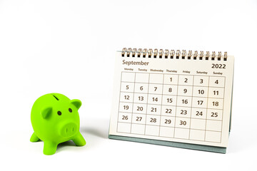 September 2022 calendar and green piggy bank on white background