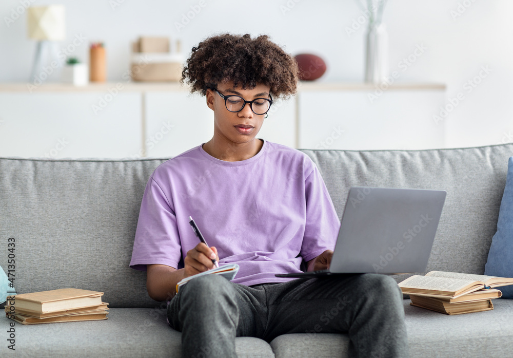 Poster e-learning. focused african american teenager having remote lesson on laptop, taking notes, sitting 