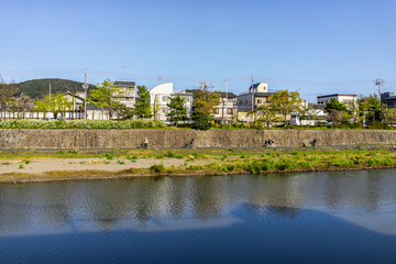 Fototapeta na wymiar Kyoto, Japan Kamo river water in evening sunset with cityscape of buildings houses on bank of canal in spring springtime
