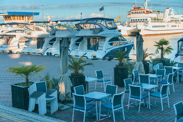 fragment of a coastal cafe on the sea embankment against the background of modern boats and ships in the Russian resort town of Sochi, Russia