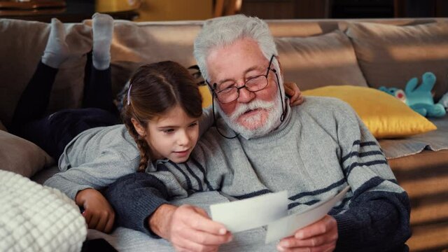Old man shows his grandchildren pictures and memories of his family album. Family pas time