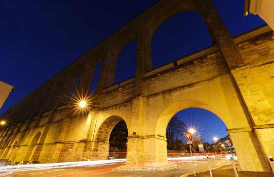 The historic aqueduct between the towns Arcueil and Cachan on the South of Paris at night , built under Henry IV.