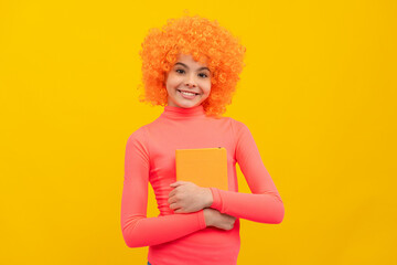 Happy girl child with orange hair in pink poloneck smile holding book yellow background, school