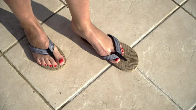Woman with manicure red nails wearing Flip Flops slippers by pool side