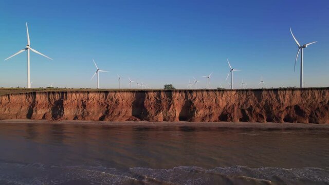 Windmills on a cliff above the sea, top view. Wind farm with turbine cables for wind energy. Renewable energy source. Drone video of onshore wind power station, view from the top, 4k. Botiyevska Ves