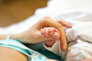 Close-up of tiny hand of newborn in mum's hand