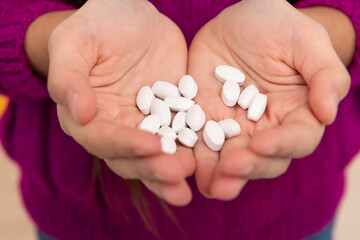 Heap of pharmaceutical oral drug product pills or pediatric vitamins in childs hands, tablets