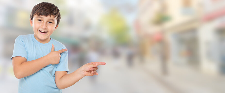 Child kid little boy showing with finger pointing on ad advertising in town with copyspace copy space