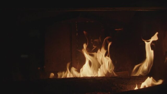 Textures of fire, embers and flames in slow motion inside a fireplace insert in a France house during winter.