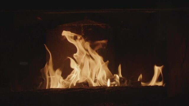Textures of fire, embers and flames in slow motion inside a fireplace insert in a France house during winter.
