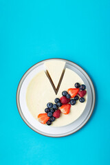 Top view of cheesecake with summer berries on blue background.