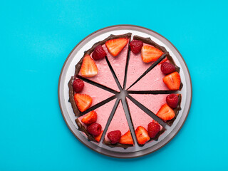 Top view of cheesecake with summer berries on blue background.