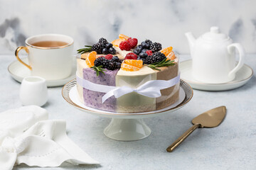 different pieces of cake decoraed fresh berries on cake stand, white table.