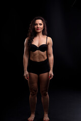 Fototapeta na wymiar Portrait of beautiful athletic woman with long curly black hair. Bodybuilding