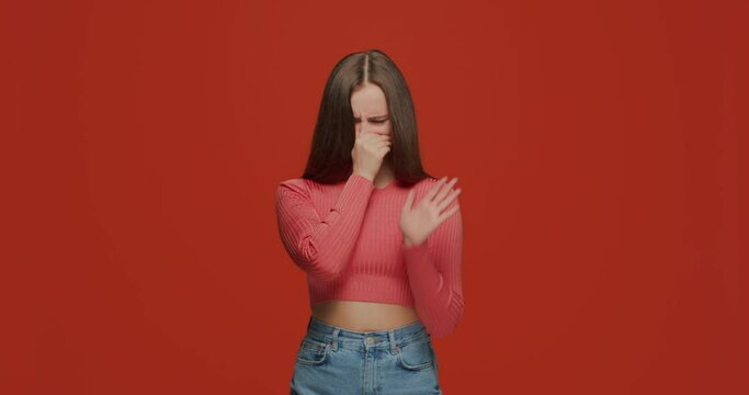 Stop bad smell. Young girl holding breath, pinching nose, gesturing stop to avoid disgusting scent