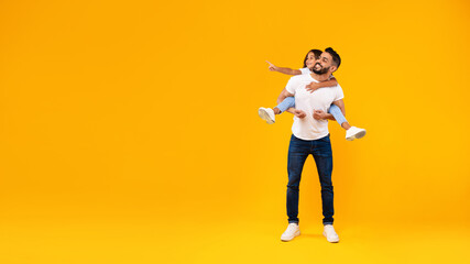 Middle-Eastern Father Carrying Daughter Having Fun Over Yellow Background, Panorama