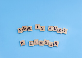 Phrase Age is just a number. Wooden blocks with lettering on a blue background. Ageism concept.
