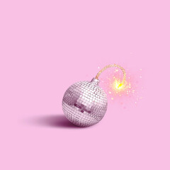 Disco mirror ball bomb with wick and sparks on pink background, creative idea. New Year and...
