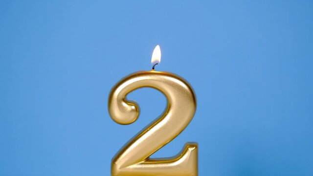 Anniversary video banner with Burning golden number two candle on Blue Background. Full HD slow motion resolution anniversary banner. Blowing out five years anniversary birthday candle.